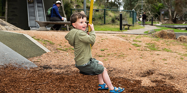 A boy using a swing at a playground.