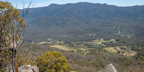 A view across a valley with some rocks in the foreground and hills and trees in the distance.